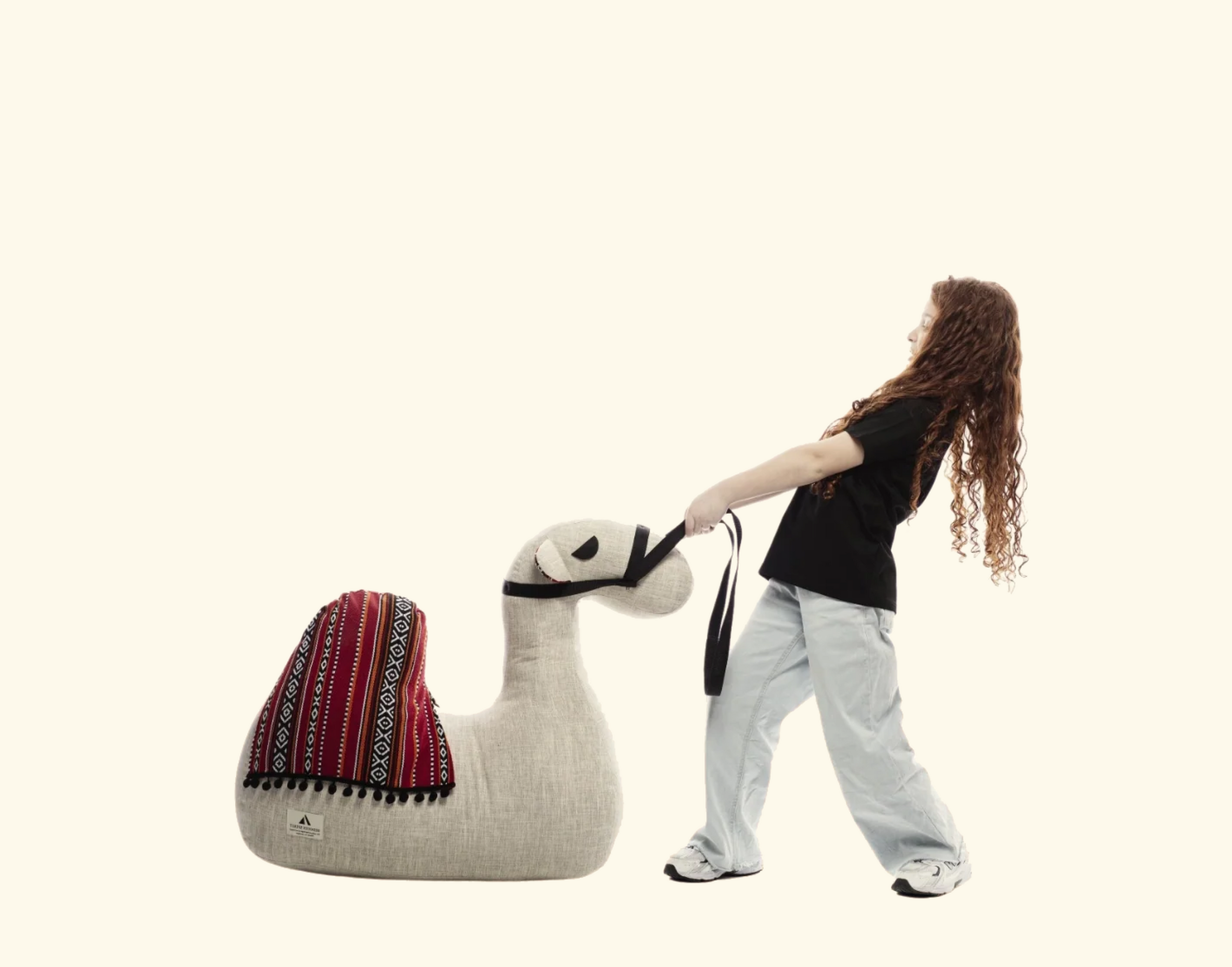 Person pulling a large, plush llama toy on a white background
