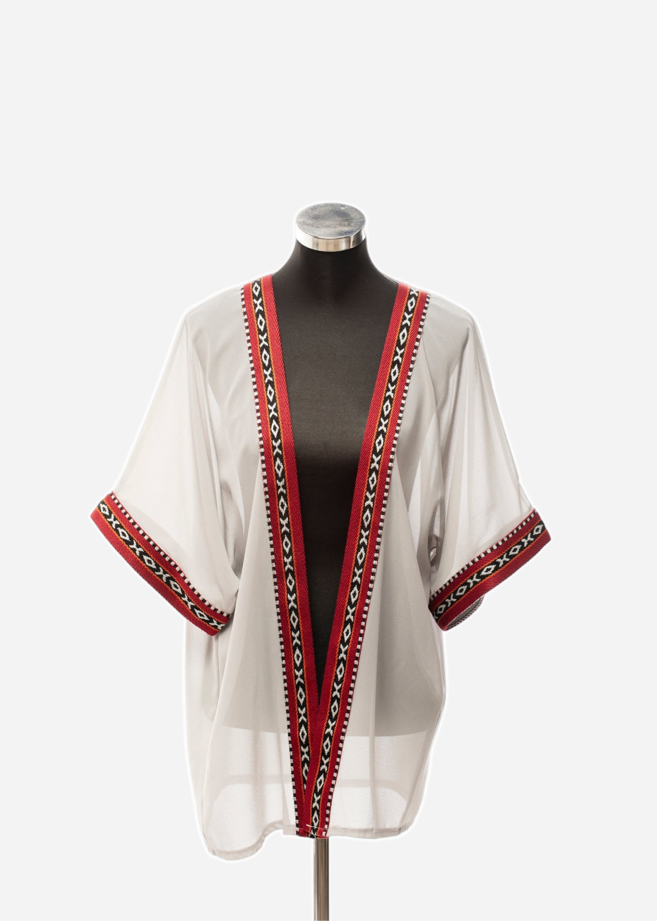 White blouse with red and black patterned trim on a mannequin against a white background