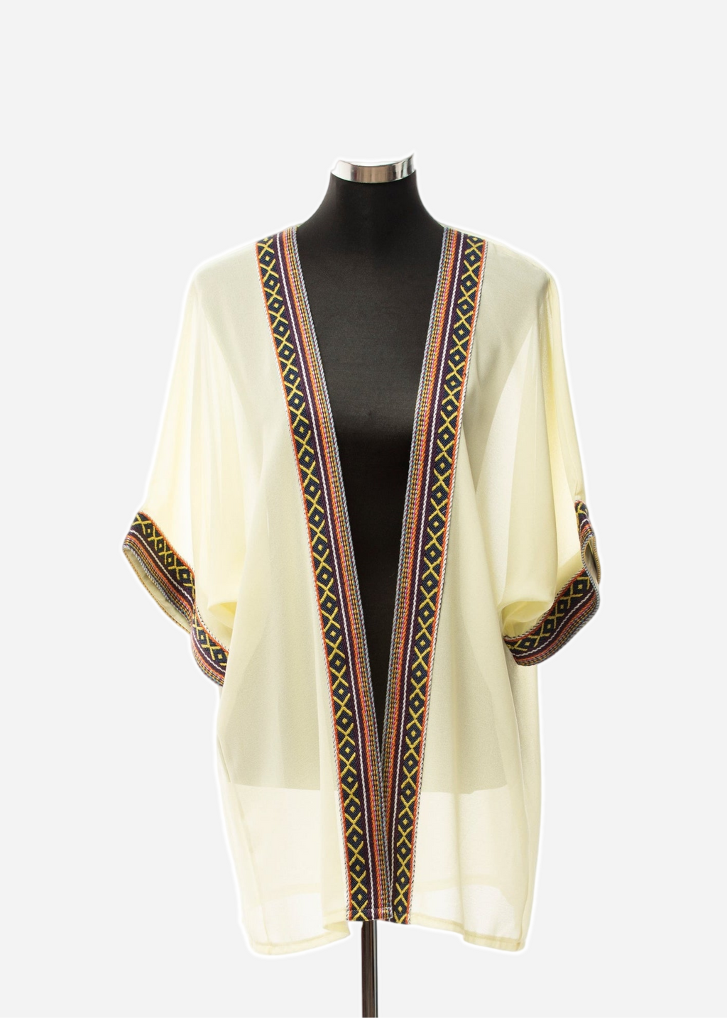 Cream-colored garment with intricate border design on a mannequin against a white background