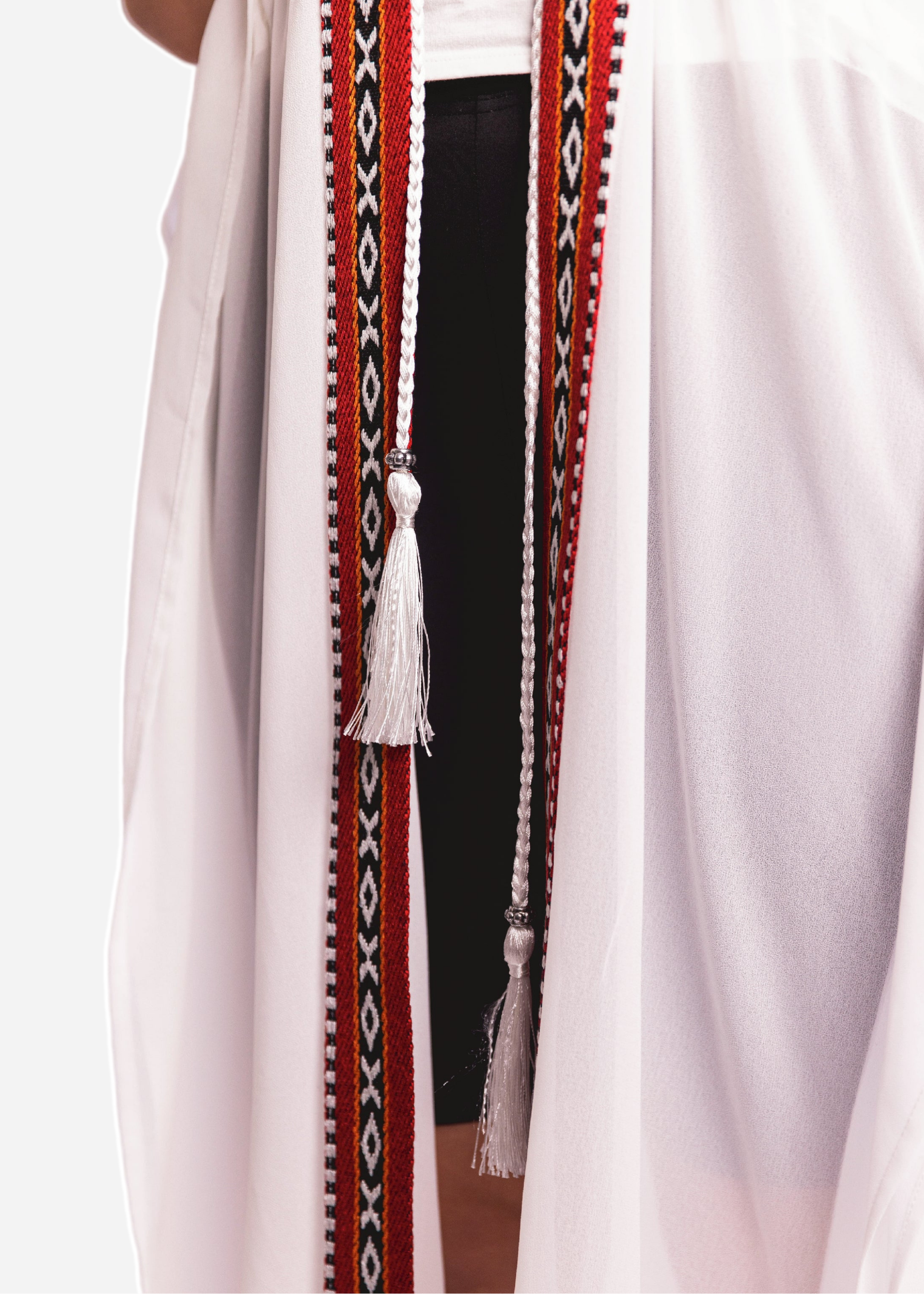 Traditional garment with decorative belt and tassel on a plain background