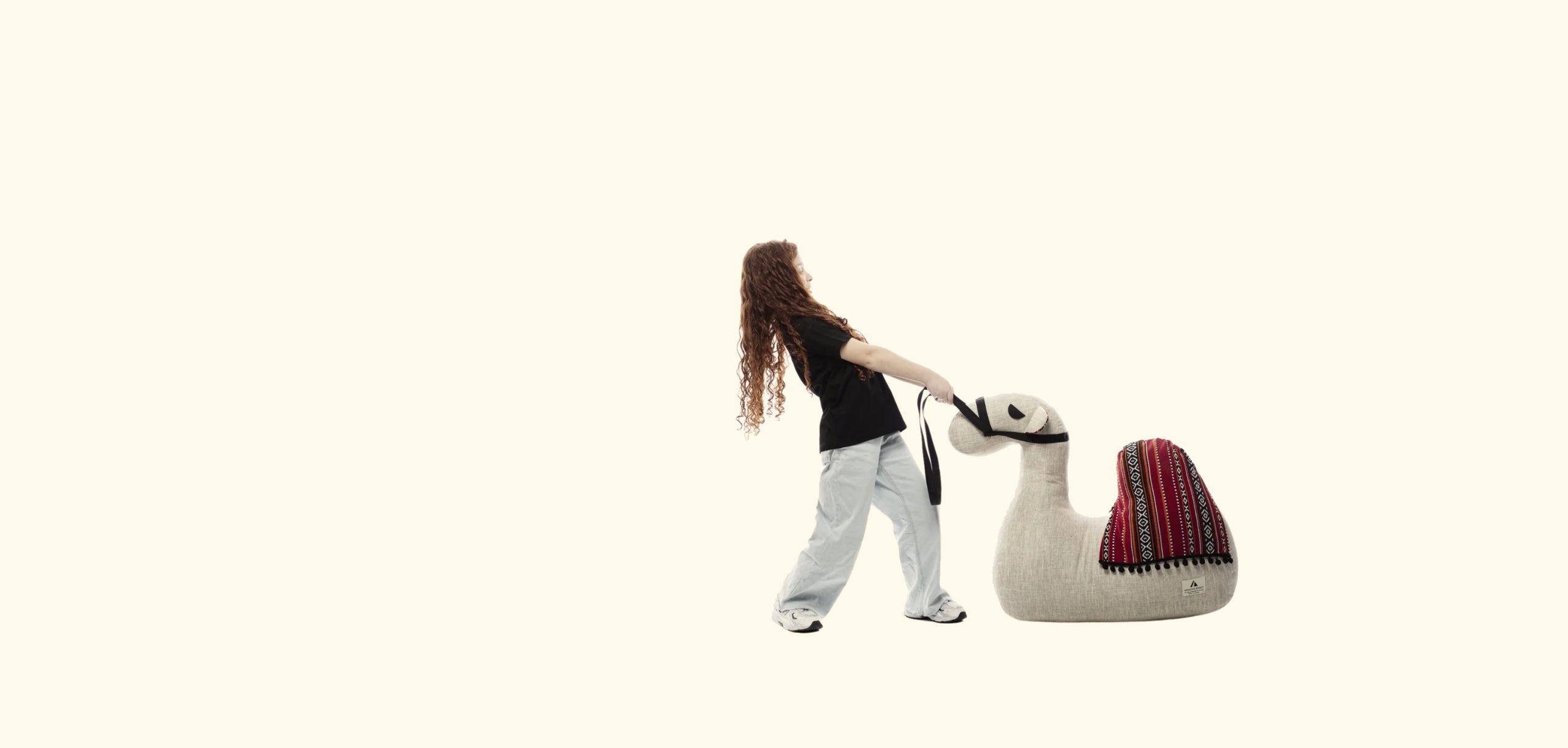Person interacting with a large stuffed llama toy on a white background